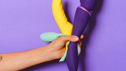 Hand holding colorful vibrators against purple background