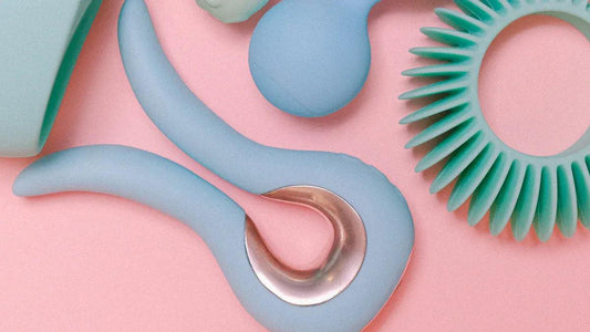 Pastel blue and mint adult toys on pink background, featuring curved silicone vibrator and textured ring