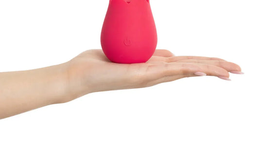 Pink silicone vibrator held in hand, compact design with power button, ideal for personal pleasure.