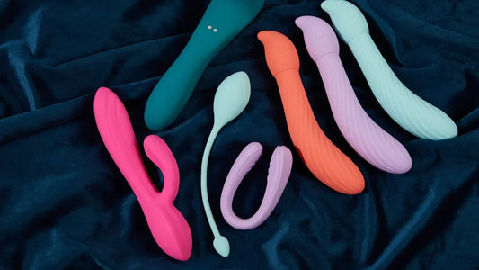 Colorful vibrators and adult toys on dark fabric, featuring premium designs for intimate pleasure.