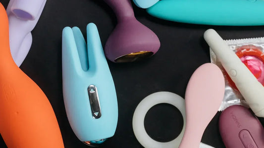 Assorted colorful adult toys including vibrators and rings on black background
