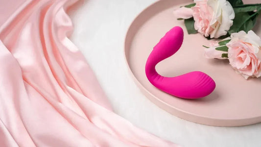 Pink curved G-spot vibrator on blush tray with roses and satin fabric