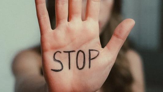 Hand with 'STOP' written on palm, signaling halt or boundary